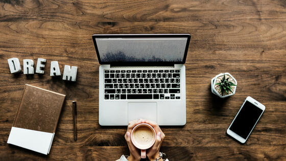 A smiling white woman in her thirties wearing a grey sweatshirt with a rainbow and the word happy on it.